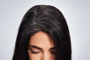 Blonde woman in winter coat and beige beanie stands at the edge of a lake in winter. 