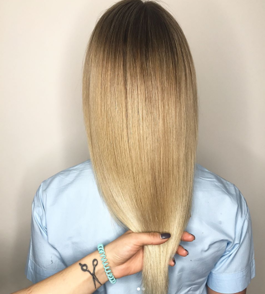 Hand holding straight, healthy, shiny blonde hair.