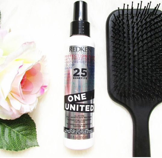 Redken One United Leave In Conditioner next to paddle brush and rose flower