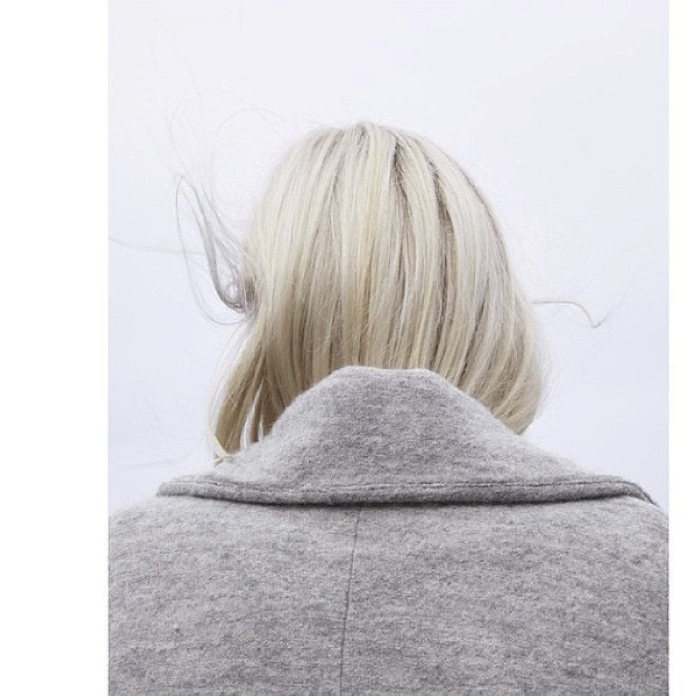 Platinum blonde hair tucked into gray coat